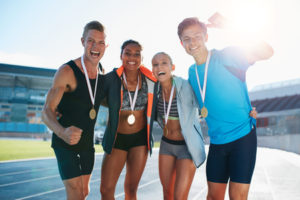 46946973 - portrait of young team of athletes enjoying victory. diverse group of runners with medals celebrating success.