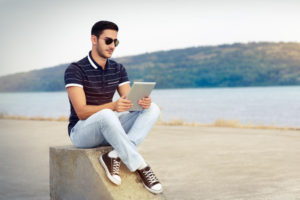39246184 - young man with sunglasses and tablet by the water